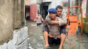 Brimob Polda Metro Jaya Gendong Warga Sakit Terjebak Banjir di Cengkareng, Jakarta Barat